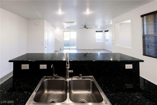 kitchen with a center island, ceiling fan, dark stone counters, and sink