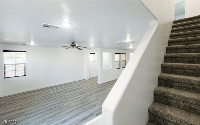 stairs featuring hardwood / wood-style floors and ceiling fan