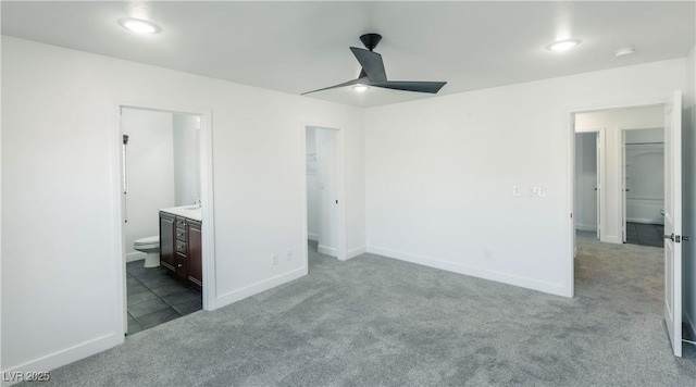 unfurnished bedroom with ensuite bathroom, ceiling fan, and light colored carpet