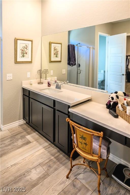 bathroom with hardwood / wood-style floors, vanity, toilet, and a shower with door