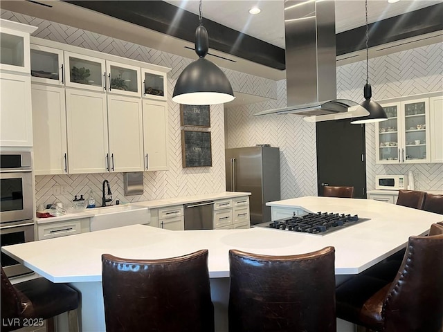 kitchen with wall chimney exhaust hood, stainless steel appliances, pendant lighting, a center island, and a breakfast bar area