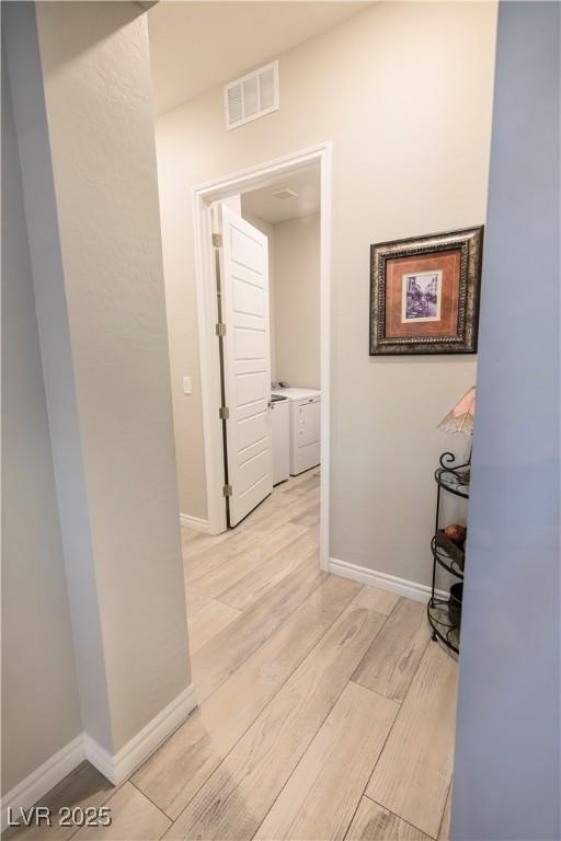 hall with washer and dryer and light hardwood / wood-style flooring