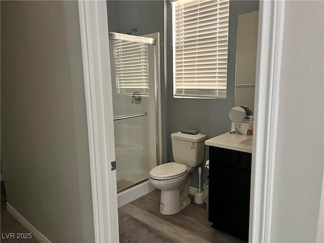 bathroom with hardwood / wood-style floors, vanity, an enclosed shower, and toilet