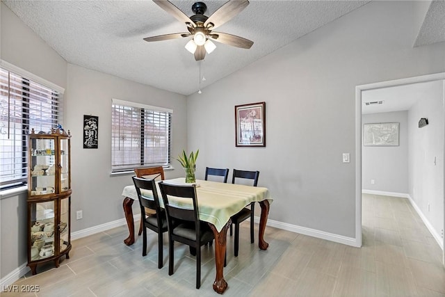 dining area with a textured ceiling, vaulted ceiling, and ceiling fan