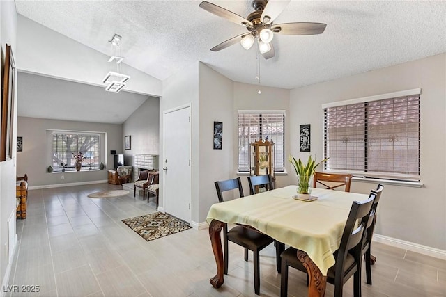 dining space with ceiling fan, lofted ceiling, and a textured ceiling