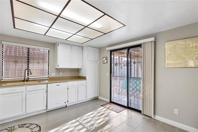 kitchen featuring white cabinets, light tile patterned floors, white dishwasher, and sink