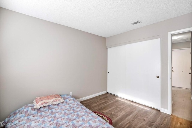 unfurnished bedroom featuring dark hardwood / wood-style floors, a textured ceiling, and a closet