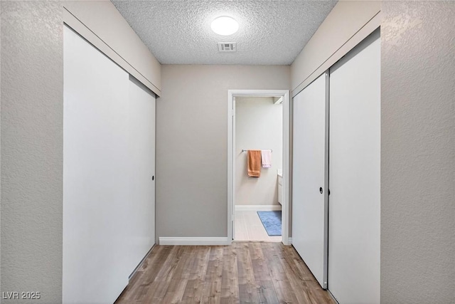 corridor featuring light hardwood / wood-style floors and a textured ceiling