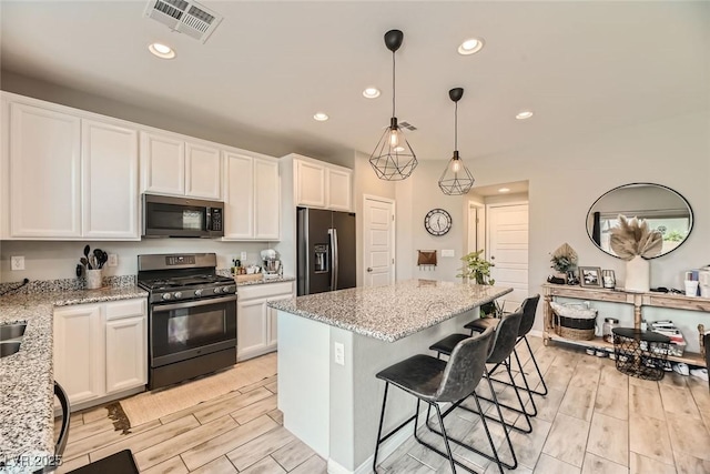 kitchen with light stone countertops, appliances with stainless steel finishes, white cabinetry, and a kitchen island