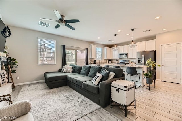 living room with light wood-type flooring, plenty of natural light, and ceiling fan