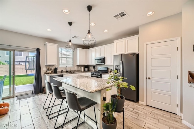 kitchen featuring white cabinets, a kitchen island, sink, and appliances with stainless steel finishes