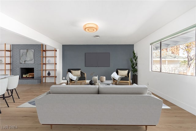 living room with a brick fireplace and light hardwood / wood-style floors