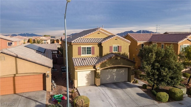 view of front of home with solar panels, a garage, and a mountain view