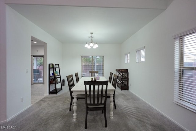 carpeted dining room featuring a healthy amount of sunlight and a notable chandelier