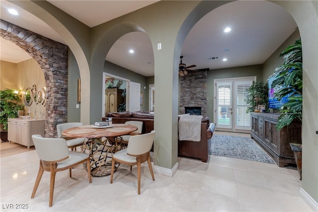 dining room featuring ceiling fan and a stone fireplace