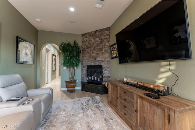 living room featuring light wood-type flooring and a stone fireplace