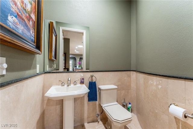 bathroom featuring toilet and tile walls