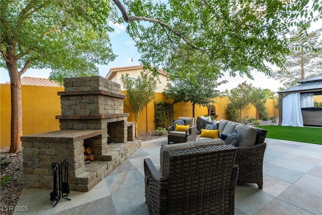 view of patio / terrace featuring a gazebo and an outdoor stone fireplace