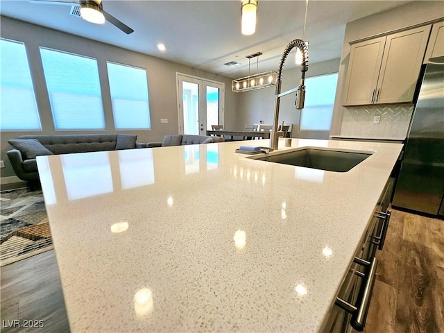 kitchen with light stone countertops, backsplash, a wealth of natural light, and sink