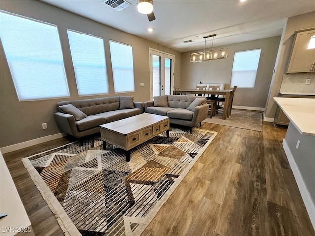 living room featuring wood-type flooring and ceiling fan with notable chandelier