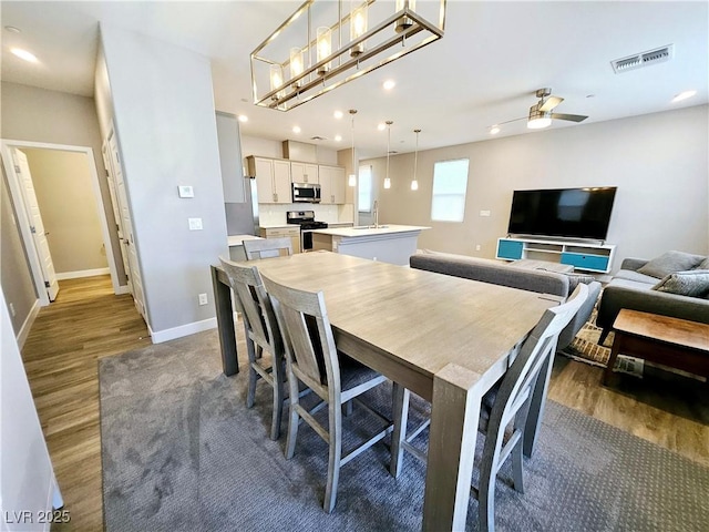 dining room with ceiling fan, dark hardwood / wood-style flooring, and sink