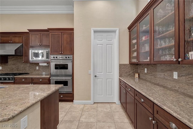 kitchen with light stone counters, ventilation hood, backsplash, light tile patterned flooring, and appliances with stainless steel finishes