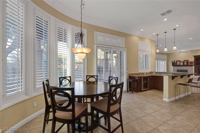 tiled dining room featuring ceiling fan, crown molding, and beverage cooler