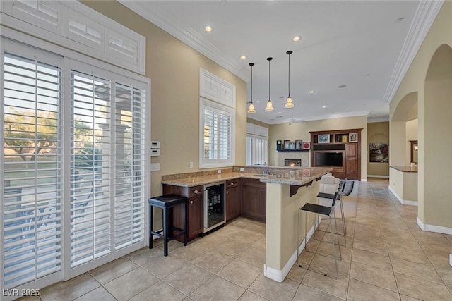 kitchen featuring light stone countertops, light tile patterned floors, a kitchen bar, and crown molding