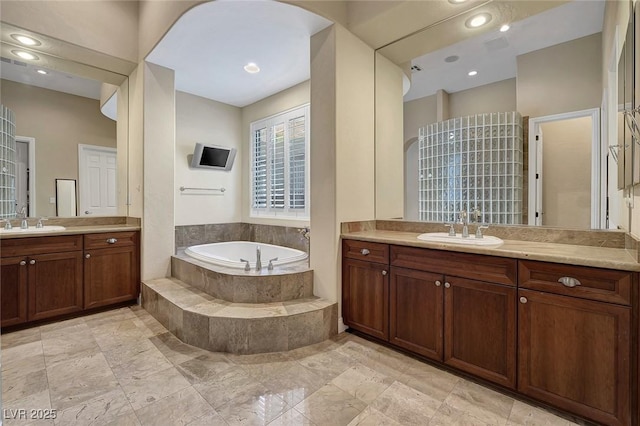 bathroom featuring vanity and a relaxing tiled tub