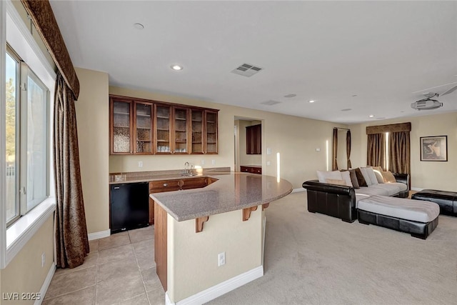 kitchen with a kitchen bar, light carpet, black dishwasher, and sink