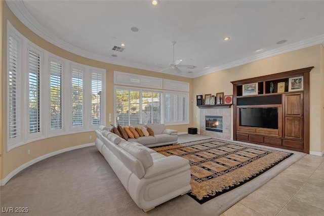 tiled living room with a tile fireplace, ceiling fan, and ornamental molding