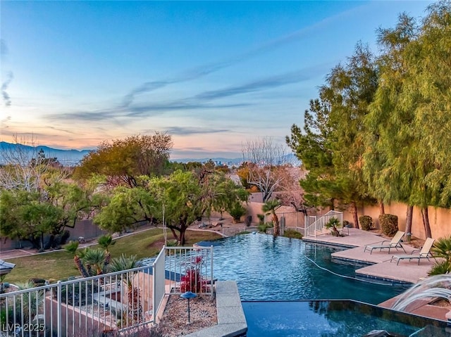 pool at dusk featuring a patio