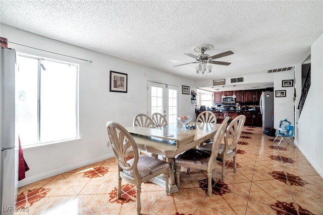 tiled dining room with ceiling fan, french doors, and a textured ceiling