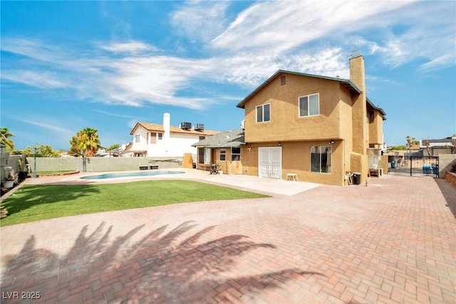 rear view of house with a yard, a patio, and a fenced in pool