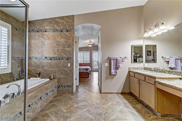 bathroom featuring tiled bath, ceiling fan, vanity, and lofted ceiling