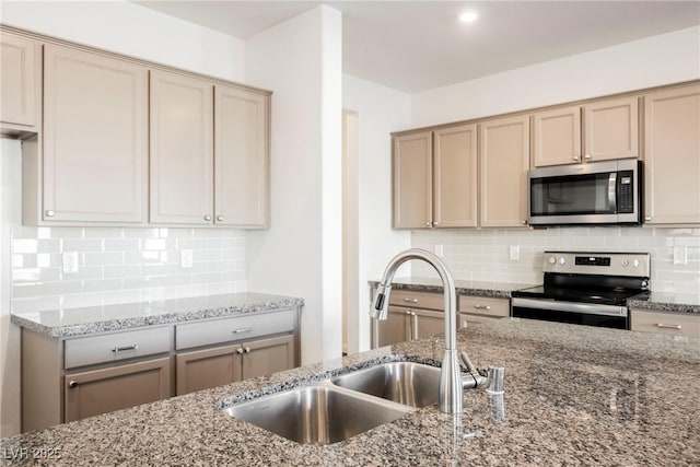 kitchen featuring backsplash, stainless steel appliances, light stone counters, and sink