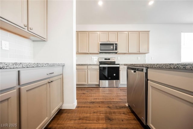 kitchen with light stone counters, cream cabinets, stainless steel appliances, and dark hardwood / wood-style floors