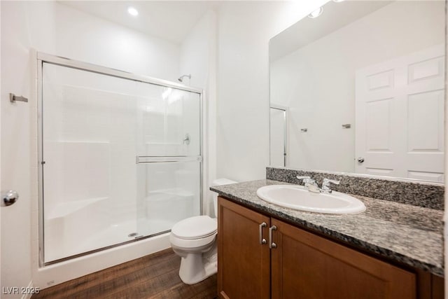 bathroom featuring wood-type flooring, vanity, toilet, and walk in shower