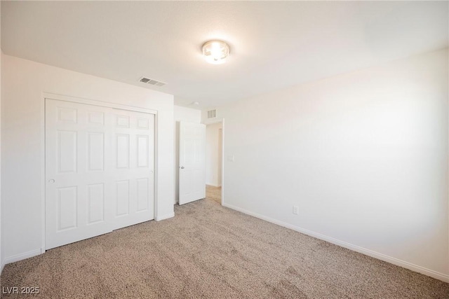 unfurnished bedroom featuring light colored carpet and a closet