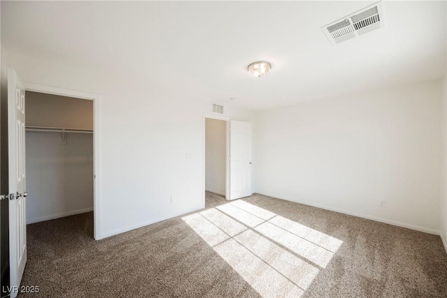 unfurnished bedroom with carpet flooring, a walk in closet, and a closet