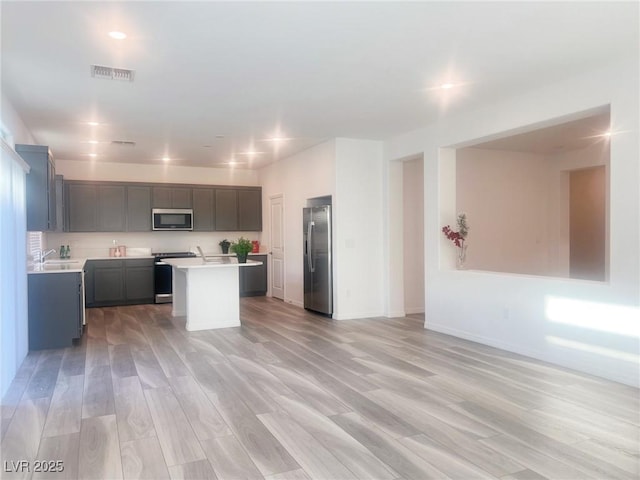 kitchen with a kitchen island, sink, light wood-type flooring, and stainless steel appliances