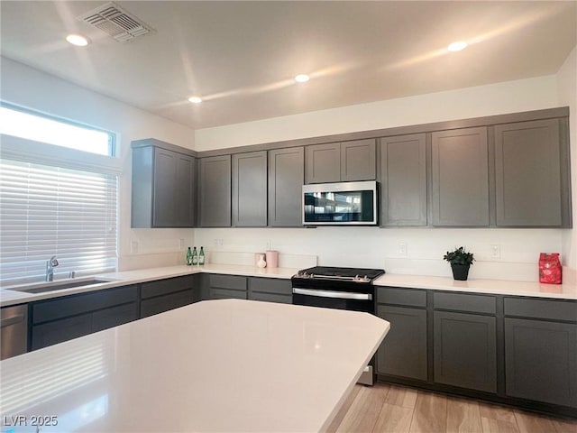 kitchen featuring light hardwood / wood-style flooring, black range with electric stovetop, gray cabinetry, and sink