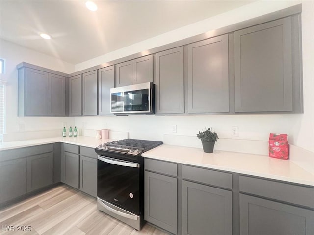 kitchen with gray cabinetry, stainless steel appliances, and light hardwood / wood-style floors