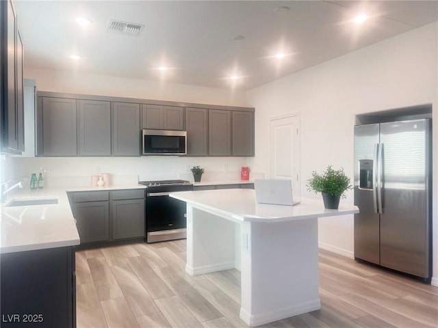 kitchen featuring a center island, stainless steel appliances, light hardwood / wood-style flooring, and sink