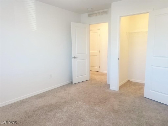 unfurnished bedroom with light colored carpet, a spacious closet, and a closet