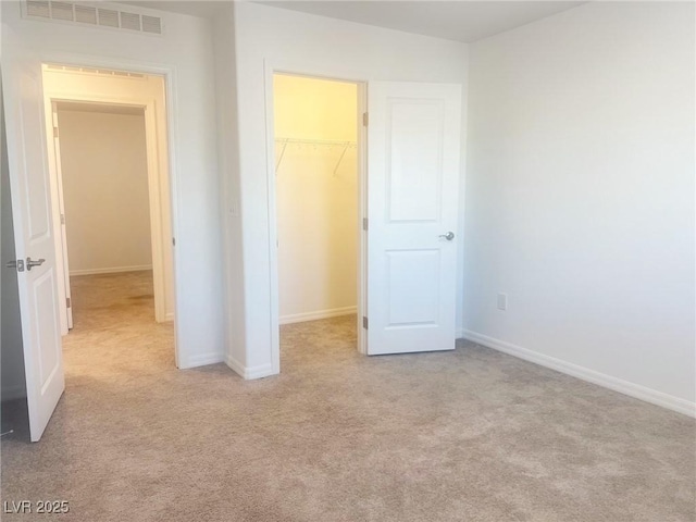 unfurnished bedroom with light carpet, a walk in closet, and a closet