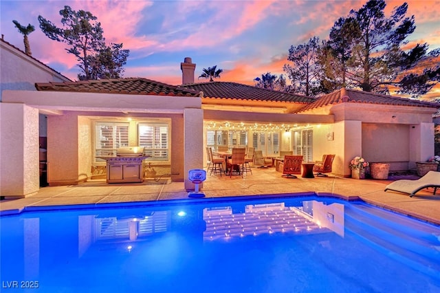 pool at dusk featuring a patio