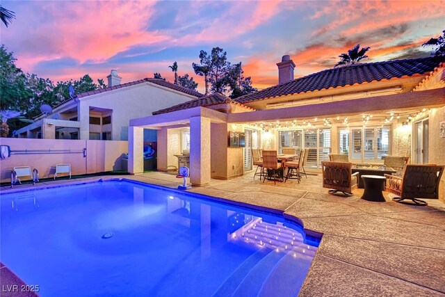 pool at dusk featuring a patio