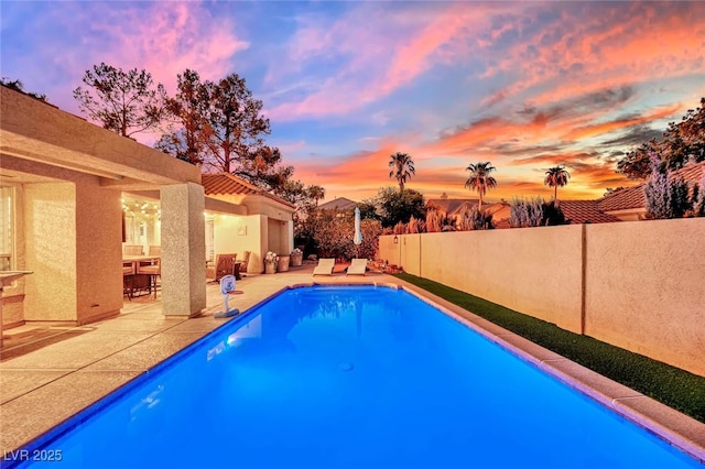 pool at dusk with a patio