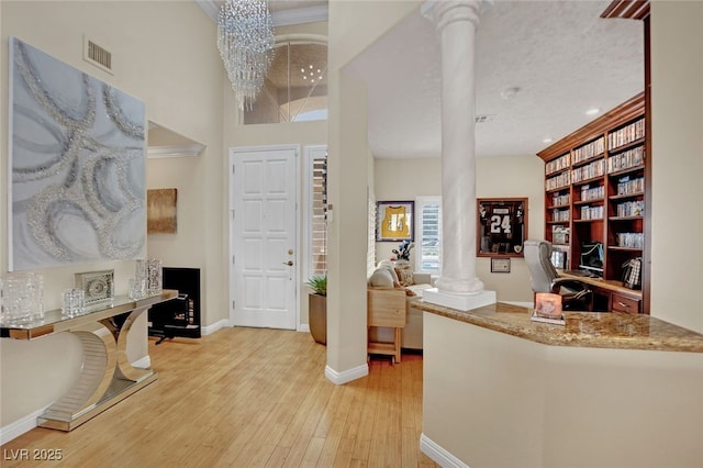 foyer featuring ornate columns, a notable chandelier, and light hardwood / wood-style floors